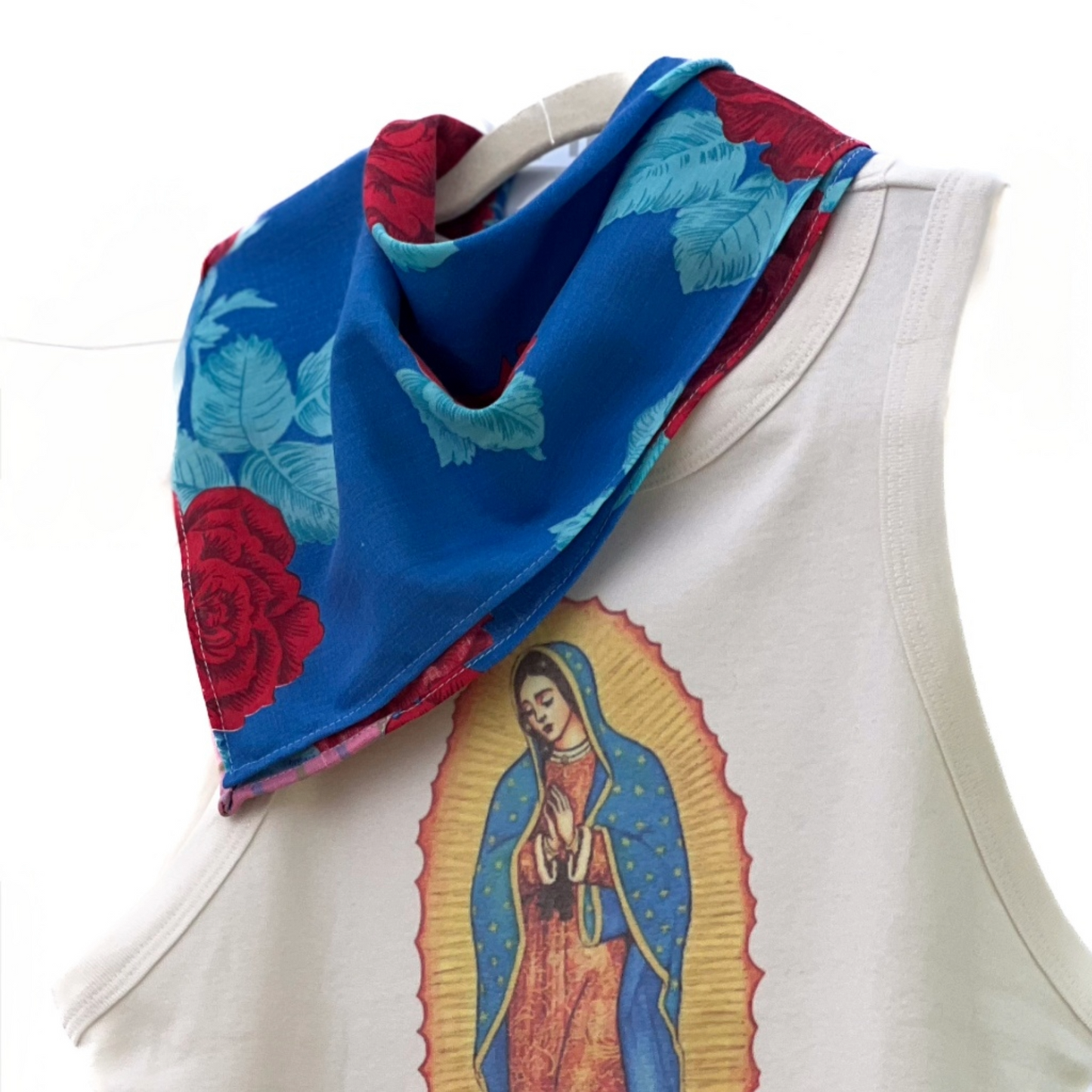 White sleeveless top with a colorful graphic of a religious figure and a blue floral scarf on a white background